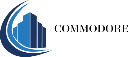 Logo of Commodore featuring a stylized blue building and curved lines on the left, with the word "COMMODORE" in black capital letters on the right.