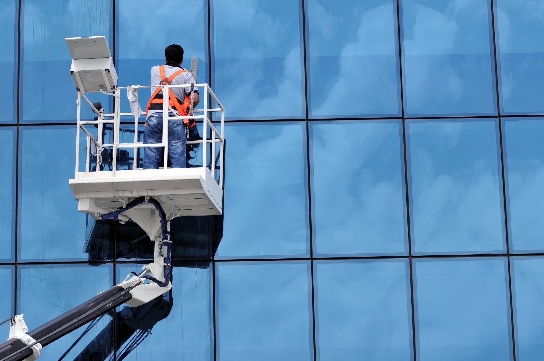 A man in a cherry picker is on the top of a crane.