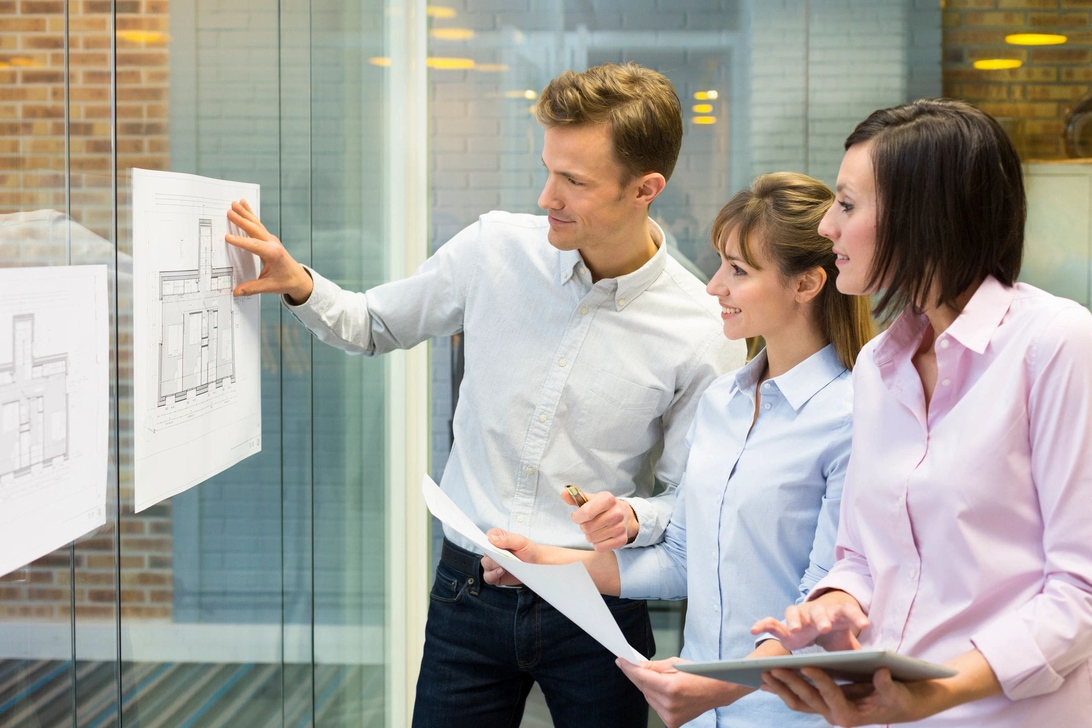 A group of people standing around looking at a board.